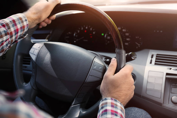 Young man holding hands on steering wheel of car - Foto, Imagem
