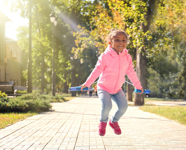 Cute African American girl skipping rope, outdoors - Photo, image