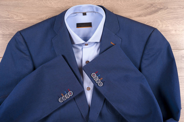 set klassieke herenkleding - blauw pak, shirts, bruine schoenen, riem en stropdas op houten achtergrond. - Foto, afbeelding