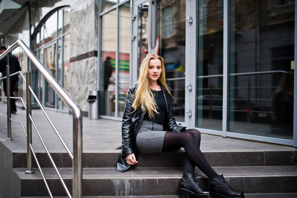 Blonde fashionable girl in long black leather coat posed at stai - Foto, immagini