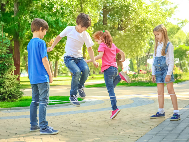 Cute little children jumping rope in park - Valokuva, kuva