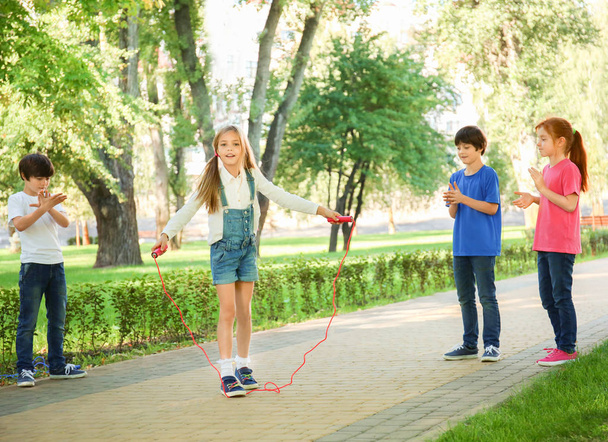 Cute little children jumping rope in park - Фото, изображение