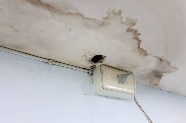 Wasser, das aus dem Dach austritt, beschädigt die Decke und verursacht die Gefahr eines Stromkurzschlusses / Problemkonzept Haus - Foto, Bild