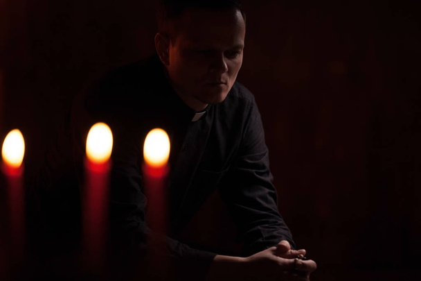 Portrait of handsome catholic priest or pastor with dog collar, dark red background. - Fotó, kép