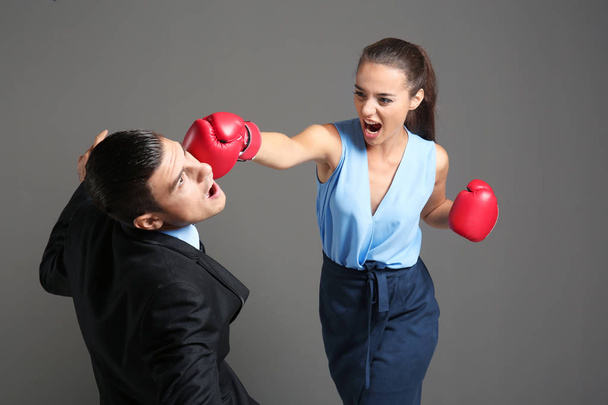 Woman in boxing gloves hitting businessman - Fotó, kép