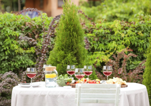 Food and wine served on table for barbecue party in garden - Foto, Imagem