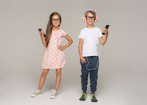 niña y niño con auriculares y teléfonos inteligentes
 - Foto, Imagen