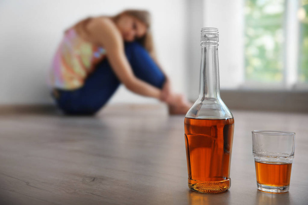 Bottle and glass of alcohol with woman on background - Foto, afbeelding