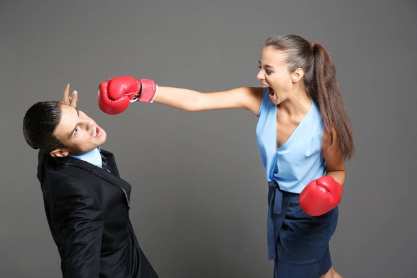 Woman in boxing gloves hitting businessman - 写真・画像