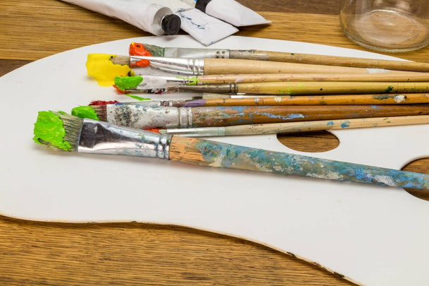 Palette d'art avec pinceaux d'art colorés avec peinture orange, jaune et verte sur fond en bois
 - Photo, image