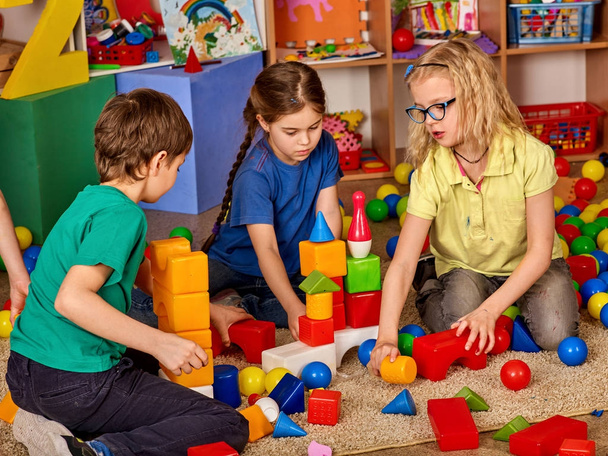 Bloki konstrukcyjne dzieci w przedszkolu. Grupa dzieci gry zabawki podłogi. - Zdjęcie, obraz