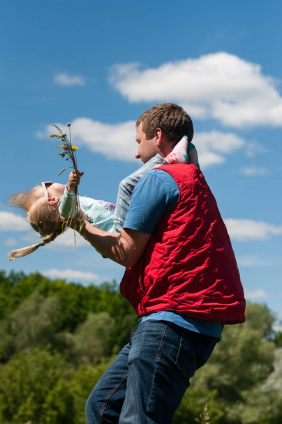 Vater wendet seine kleine Tochter im Sommer gegen den Himmel - Foto, Bild