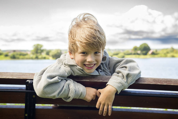 Nehir adam parkta bir bankta sarışın çocuk gülümseyen - Fotoğraf, Görsel