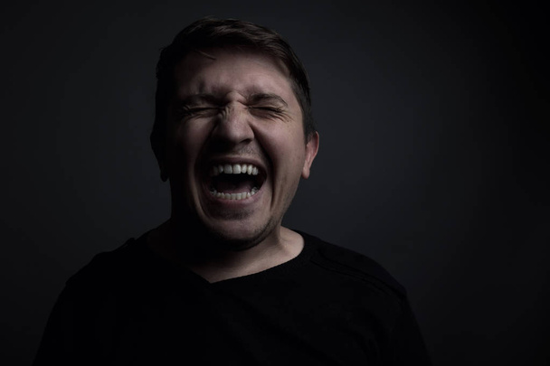portrait of man yell of pain in front of grey background - 写真・画像