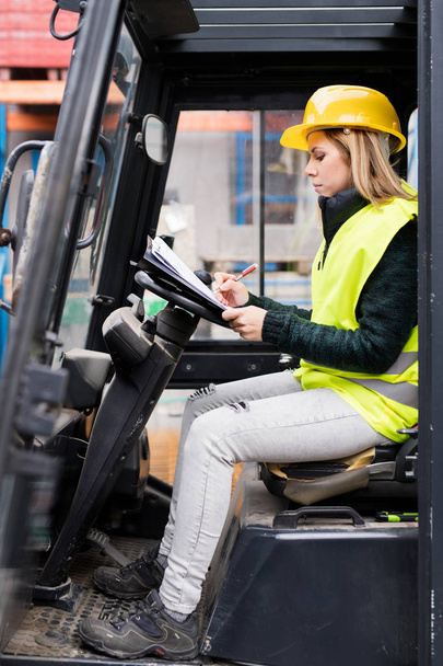 Female forklift truck driver outside a warehouse. - Foto, afbeelding