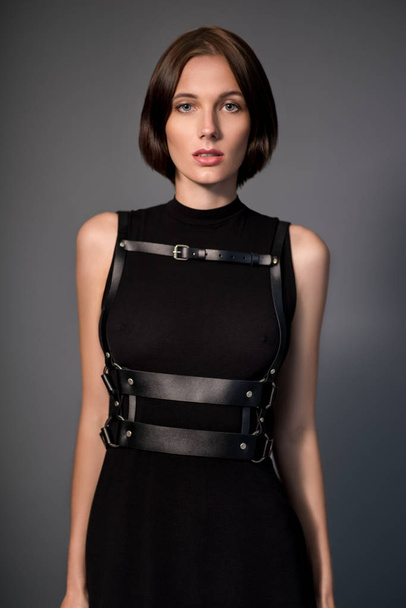 woman in black dress with leather accessories - Foto, afbeelding