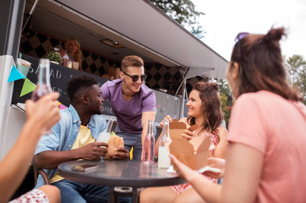 amigos felizes com bebidas comendo no caminhão de comida
 - Foto, Imagem
