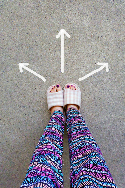 Naiset käyttävät kodin tohvelit jalat nuolilla piirretyt valinnat suunta betonitaustalla
 - Valokuva, kuva