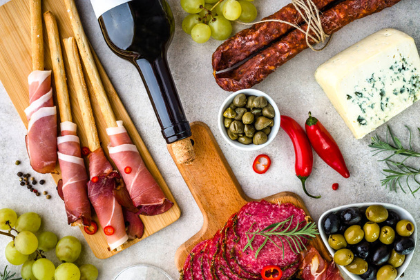Mix of spanish tapas and italian antipasti, prosciutto with bread, wine and other selection of food on table, mediterranean diet - Foto, Imagen