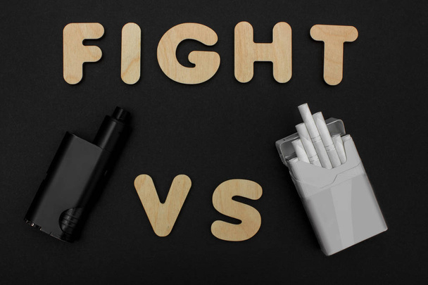Cigarettes against Vape. Electronic cigarette over a dark background. Popular devices of year - modern vaping device. - Photo, Image