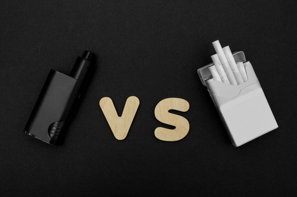 Cigarettes against Vape. Electronic cigarette over a dark background. Popular devices of year - modern vaping device. - Photo, Image