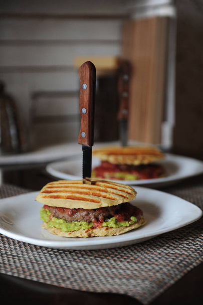Sığır eti ile Burger, Guakamole, vişne sosu, patates topuz ızgara pirzola. Ahşap Saplı bir bıçak ile bıçakladı - Fotoğraf, Görsel