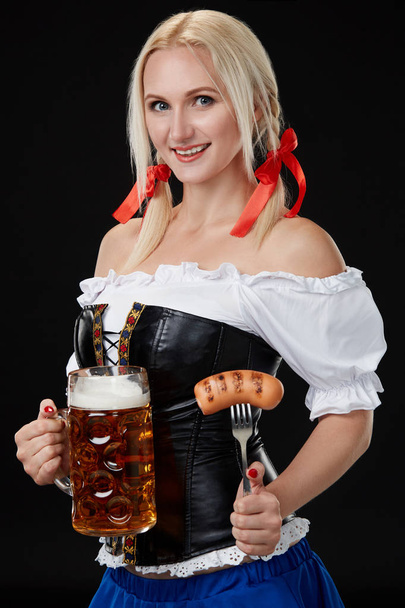Waitress in traditional german costume holding beer glass on Oktoberfest. - Foto, afbeelding