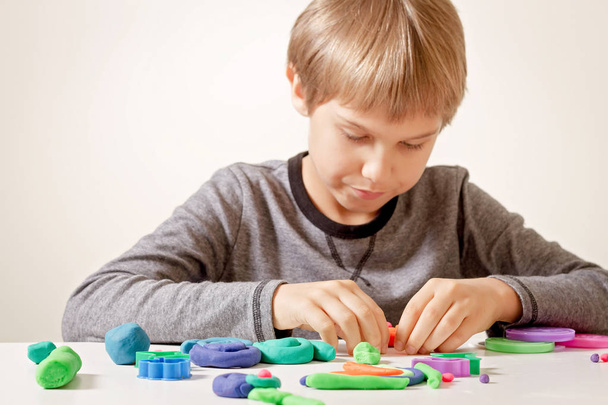 Το παιδί παίζοντας και δημιουργώντας από άργιλο διαμόρφωσης ή πλαστελίνη. - Φωτογραφία, εικόνα