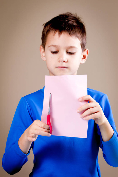 Boy cutting colored paper with scissors - Foto, Bild