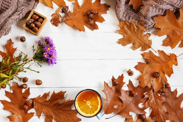 Top view of Cup of tea with autumn leaves, a warm scarf on wooden background with copyspace in center. top view - 写真・画像