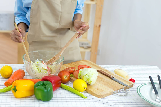 Здорова жінка робить свіжий овочевий салат з оливковою олією, помідорами та салатом для дієти та здорового харчування
.   - Фото, зображення