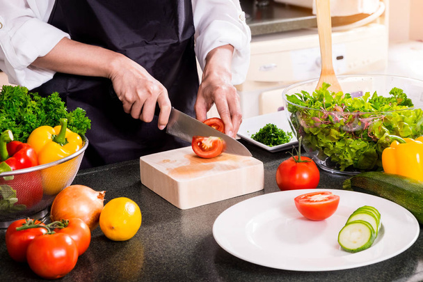 Mulher saudável faz salada de legumes frescos com azeite, tomate
 - Foto, Imagem