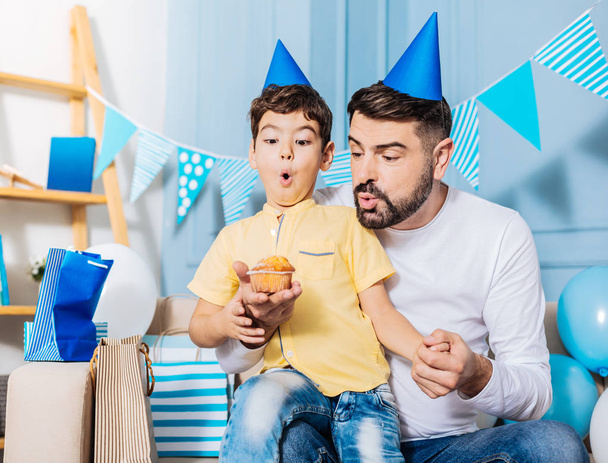 Pleasant father helping little son blow out birthday candle - Zdjęcie, obraz