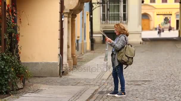 woman traveler with map looking for building in European city  - Materiał filmowy, wideo