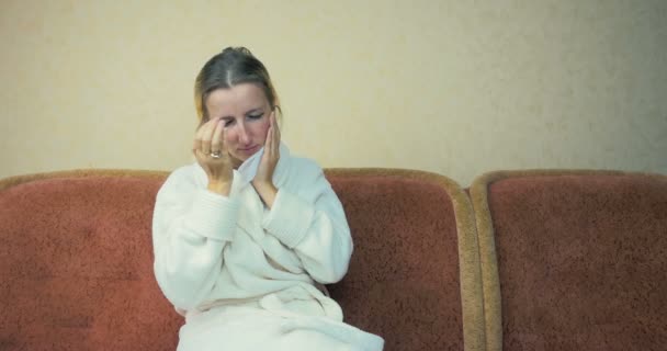 Jong meisje in een home badjas hoest en niest om thuis te zitten op de Bank. - Video