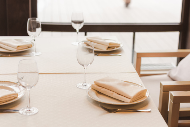 Mesa servida con gafas de vino y platos con servilletas
 - Foto, Imagen