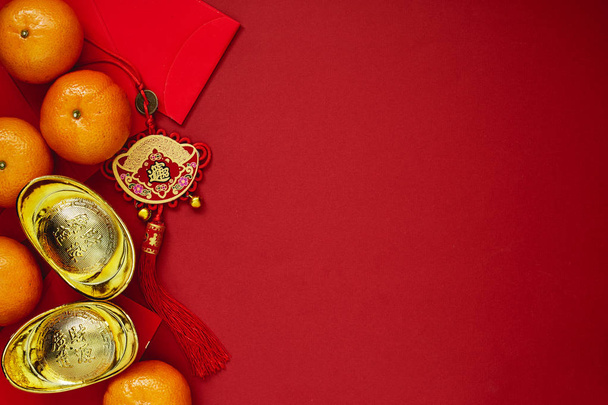 Monete cinesi di fortuna o nodo cinese e lingotti d'oro cinesi e nodo tradizionale cinese (testo straniero significa benedizione) e buste rosse e decorazione con arance fresche su sfondo di carta rossa
 - Foto, immagini