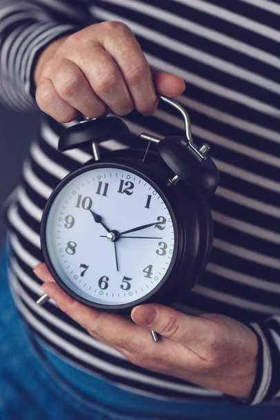 Time is passing, female hand with vintage alarm clock - Fotó, kép