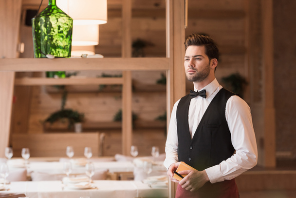 Waiter standing with notebook and pen - Photo, Image