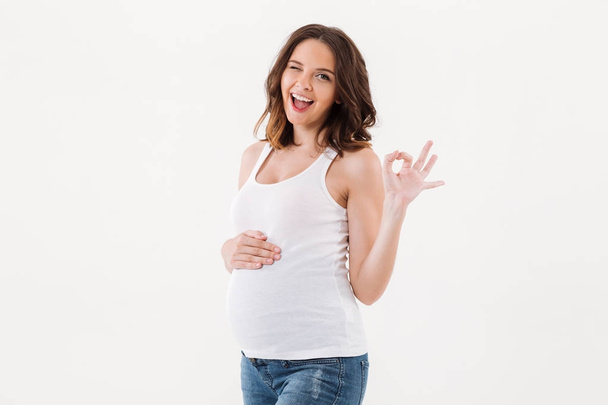 Cheerful pregnant woman showing okay gesture. - Фото, изображение