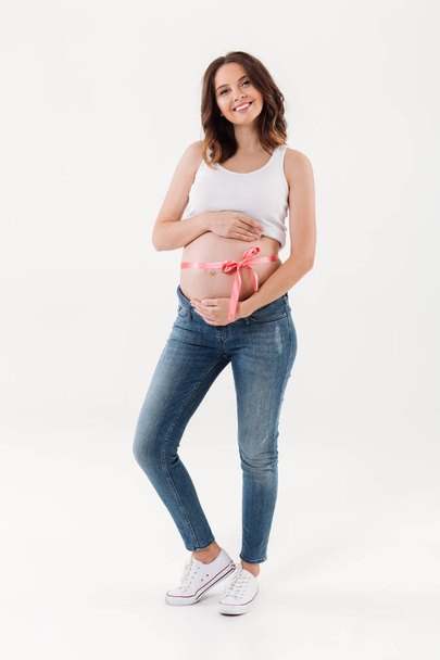 Pregnant woman standing isolated with a bow on the belly - Foto, Imagen