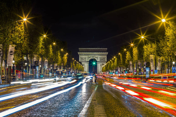 ライトアップされた凱旋門、パリのシャンゼリゼ通り。有名な観光場所や輸送の概念。夜街灯交通と都市の景観。長時間露光。トーン - 写真・画像