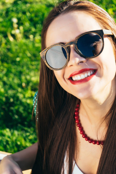 Close up woman face in sunglasses,wooden glasses,white smile - Foto, afbeelding
