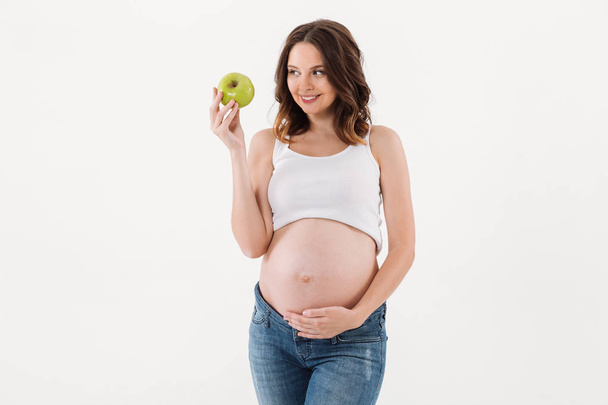 Happy pregnant woman eating apple - Fotó, kép