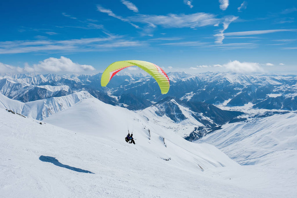 Parapente voando entre os picos nevados irregulares
 - Foto, Imagem