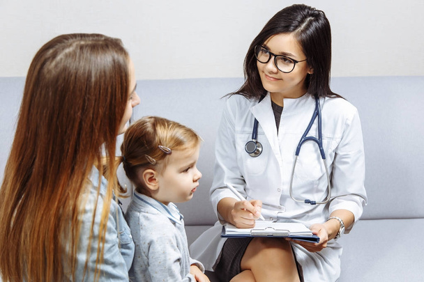 Little girl and her young mother are consulting with pediatrician in his office. - 写真・画像