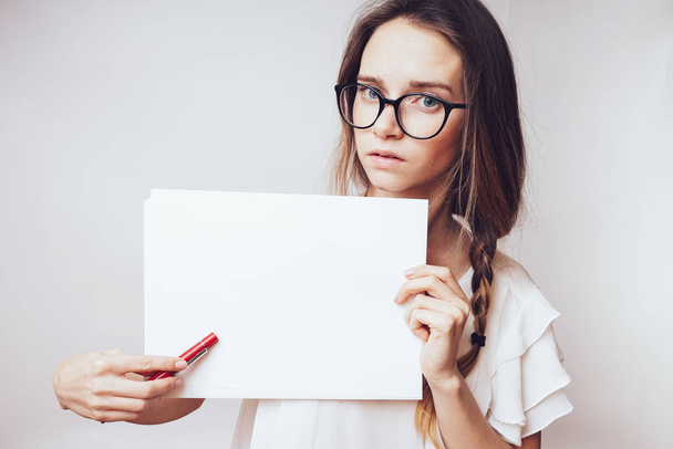 Sad attentive woman point to paper,in a white T-shirt and glasses - Photo, image