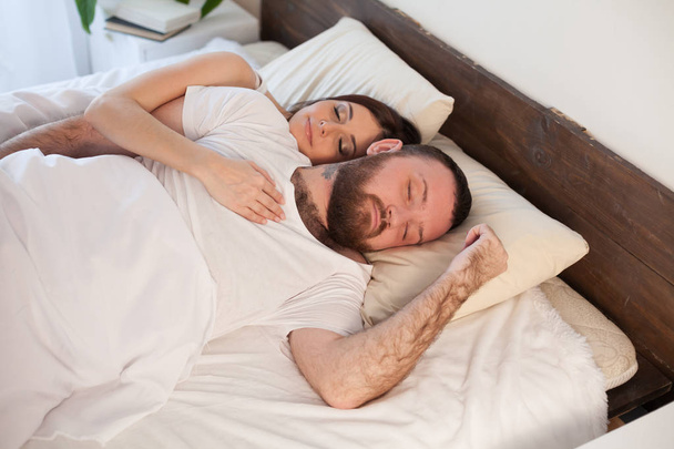 bir erkek ve bir kadın beyaz yatakta bir yatak odasında uyuyan - Fotoğraf, Görsel