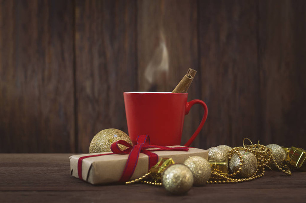 Packaged gift, red cup, cinnamon, golden balls, beads - Fotoğraf, Görsel