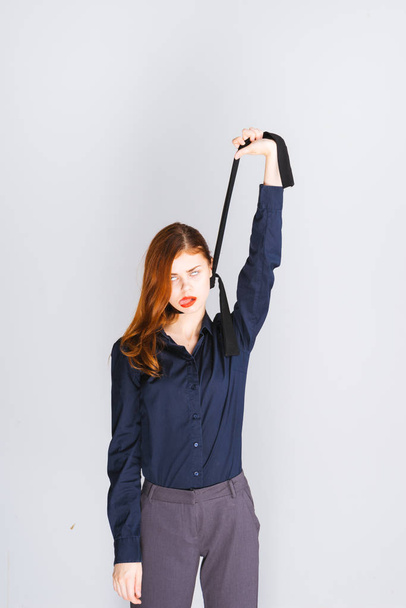 stylish red-haired girl in dark clothes pretends to hang herself on a tie - Fotoğraf, Görsel
